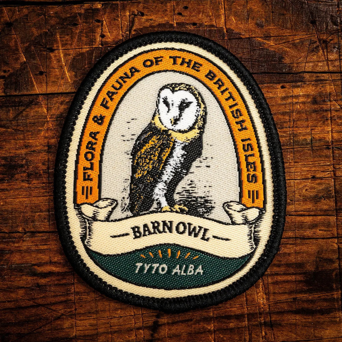 An oval embroidered patch featuring a barn owl illustration with the text 'FLORA & FAUNA OF THE BRITISH ISLES' and 'BARN OWL TYTO ALBA' on a rustic wooden background.