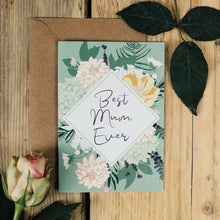 Floral card with 'Best Mum Ever' text on a wooden surface with leaves and a rose.