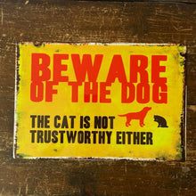 Vintage-style 'Beware of the Dog, The cat is not trustworthy either' sign on a wooden background.