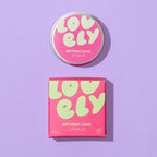 Lovely Skincare Birthday Cake lip balm with packaging on a purple background background.