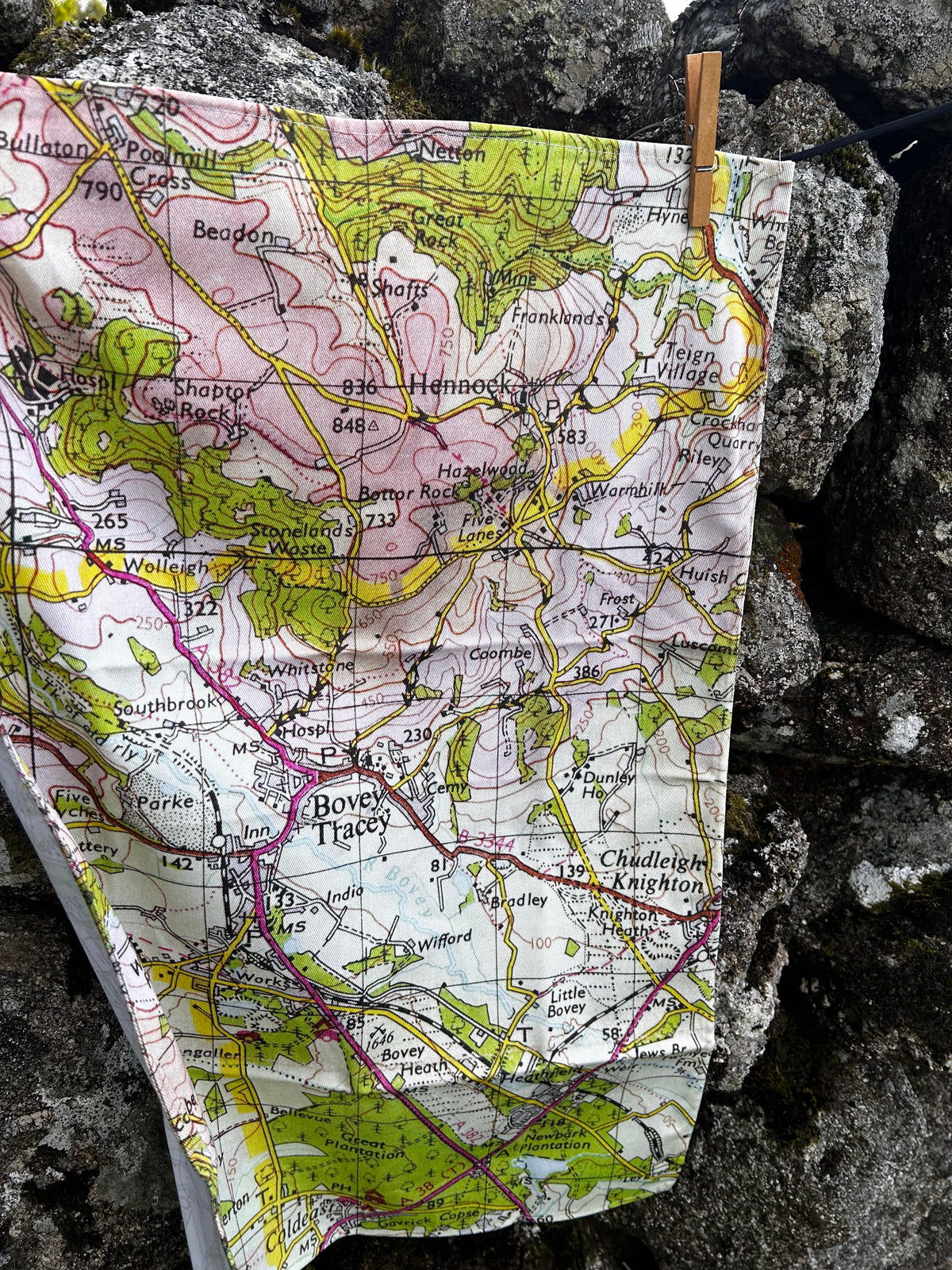 Close up of Bovey Tracey map tea towel, photographed against a stone wall.