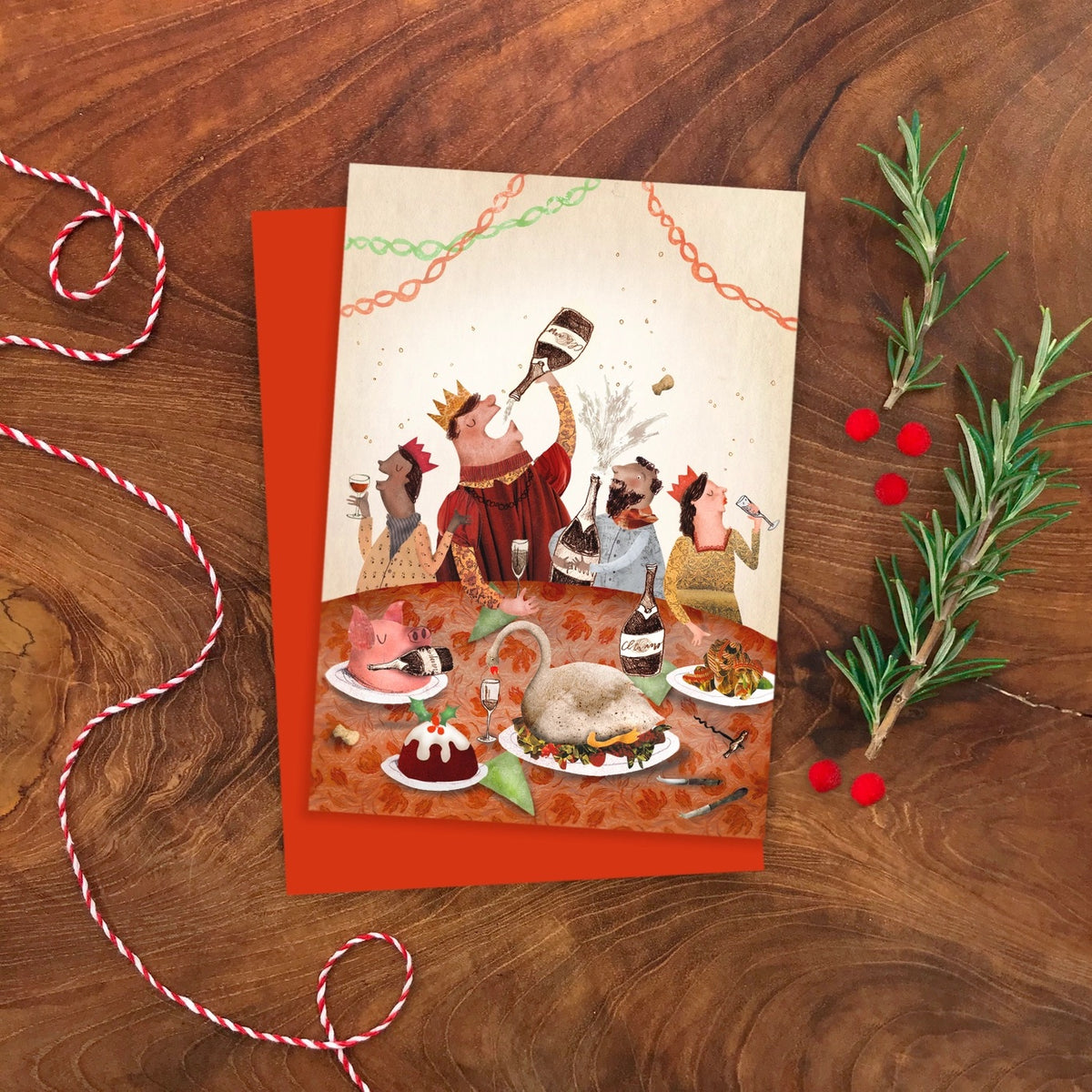 Greeting card with festive illustration of people celebrating with champagne at a table on a wooden surface with decorative elements.