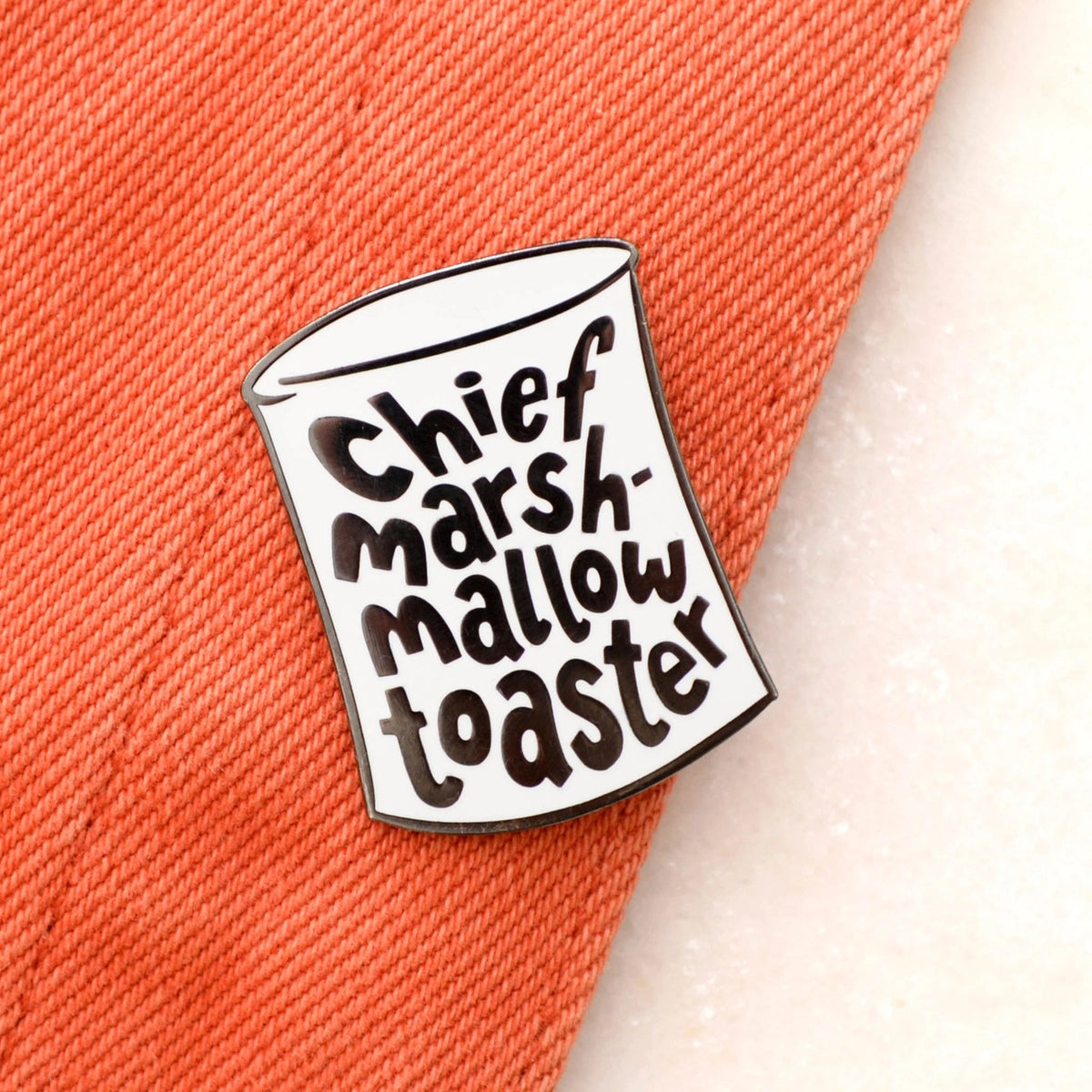 Pin with 'Chief Marshmallow Toaster' text on a textured surface