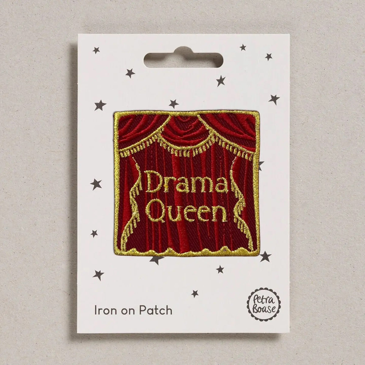 An embroidered iron-on patch featuring a red curtain with gold fringe and the words 'Drama Queen' in gold lettering, mounted on a white backing card with star illustrations and the text 'Iron on Patch' and 'Petra Boase'.
