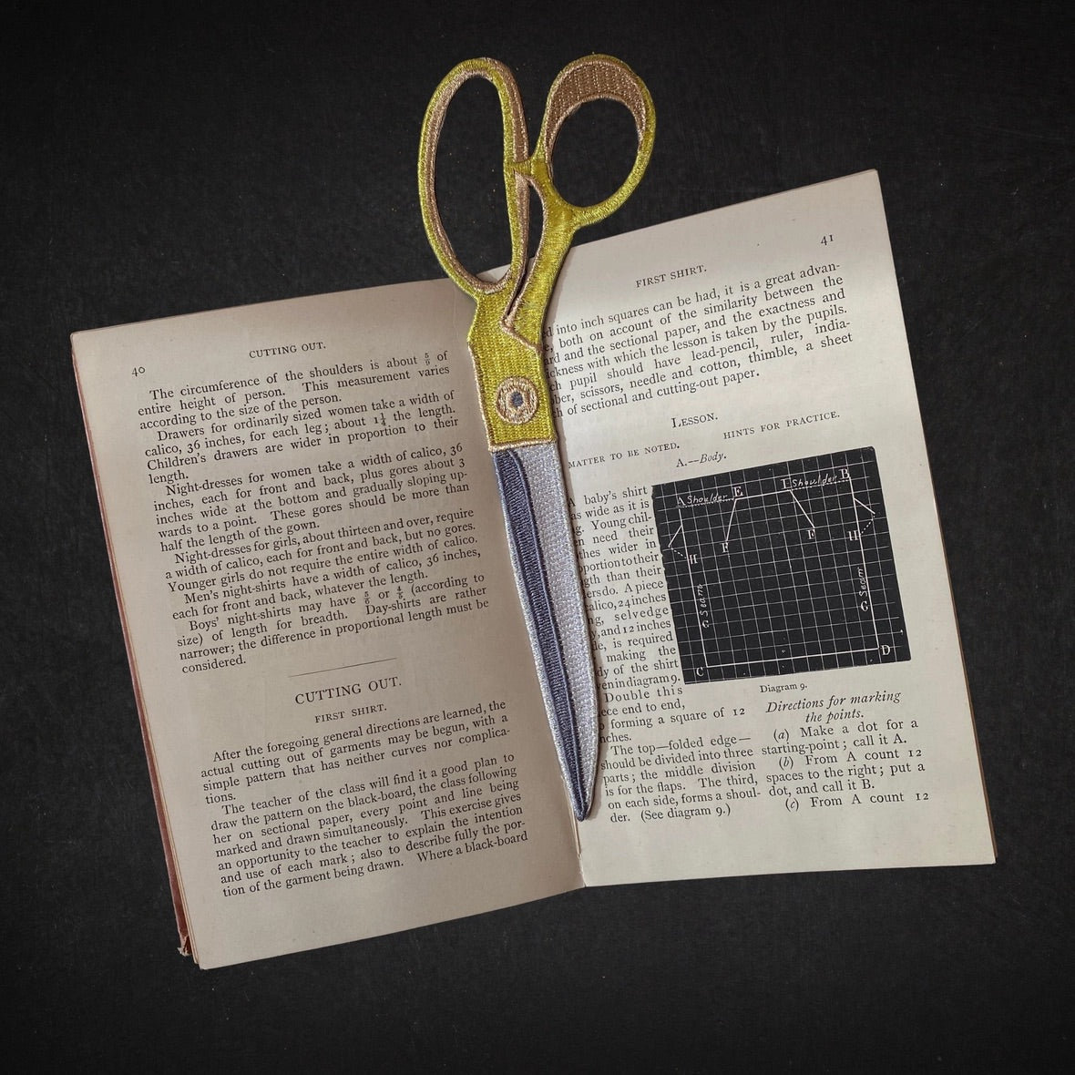 Embroidered Scissors  bookmark on an open book with text and diagrams
