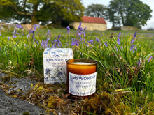 Bluebell candle in glass jar with bluebells, barn and trees in background