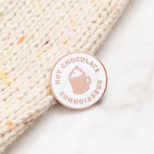 Pin with 'Hot Chocolate Connoisseur' text and chocolate mug design in a pale copper colour against a white background