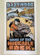 Tea towel featuring Illustration of a person with a large rock, titled 'Dartmoor Home of the Huggable Rock', on a beige background.