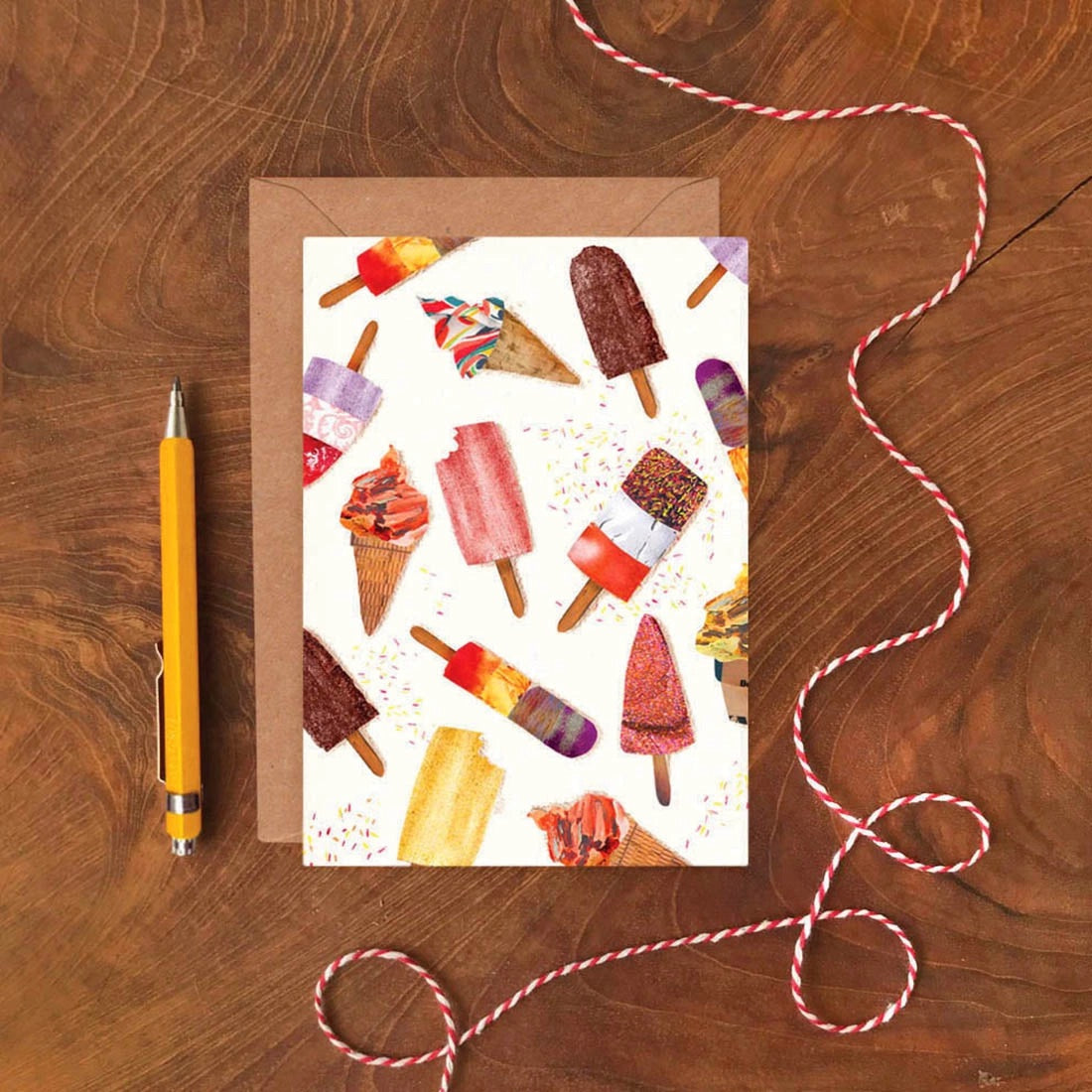 Greeting card with ice cream illustrations on a wooden surface with a pen and string.