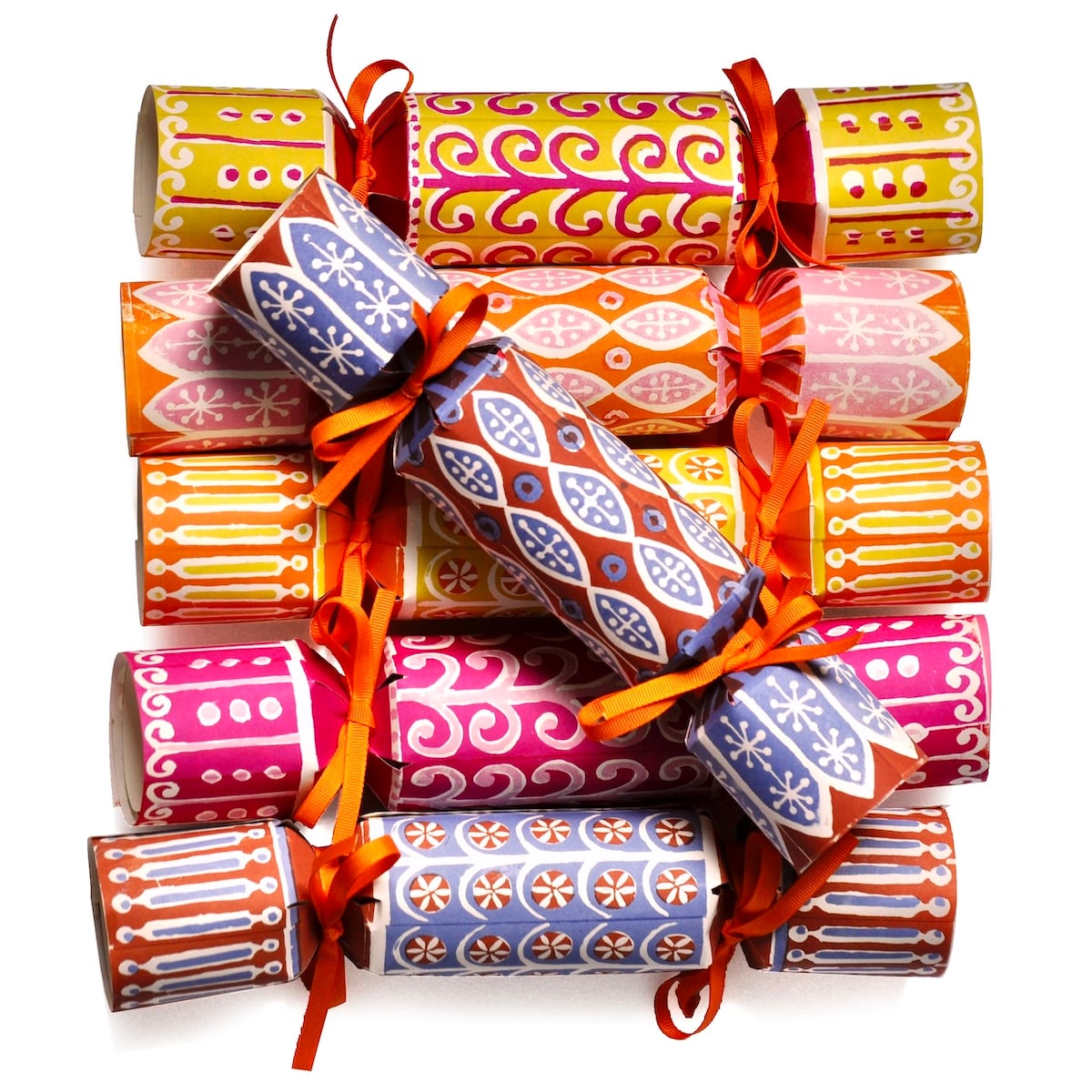A stack of colourful Cambridge Imprint Christmas crackers with orange ribbons, featuring various festive patterns in pink, orange, yellow, and blue on a white background.