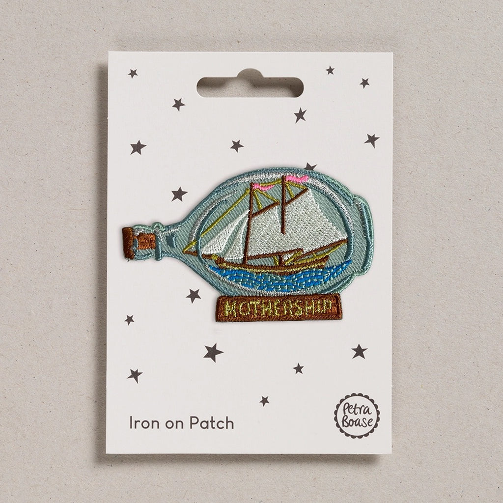 Iron on patch of a ship in a bottle with 'Mothership' text on a white card, brand 'Petra Boase' visible.