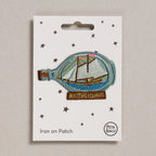 Iron on patch of a ship in a bottle with 'Mothership' text on a white card, brand 'Petra Boase' visible.