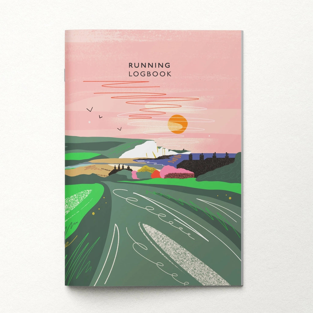 A running logbook with a colourful illustrated cover showing a landscape with green fields, hills, a pink sky, and an orange sun. The title 'RUNNING LOGBOOK' is printed at the top.