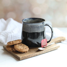 Black mug with a spoon and cookies on a wooden board with cookies on the side.
