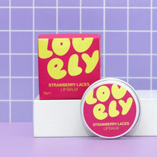 Lovely Skincare's Strawberry Laces lip balm shown with its pink and yellow box and a round metal tin against a purple tiled background.