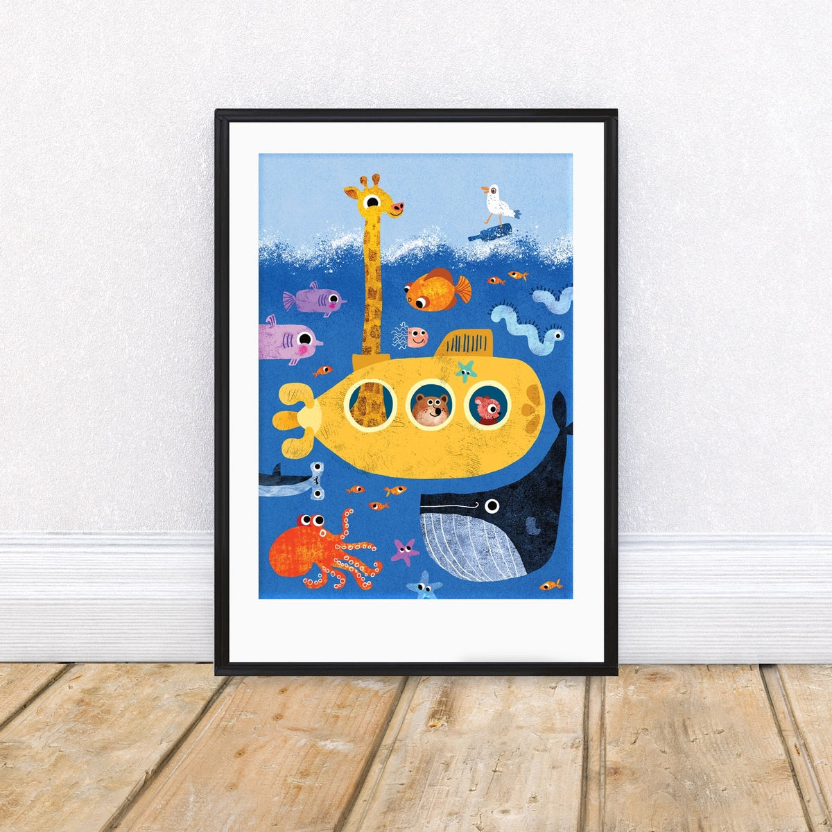 Framed children's illustration of a yellow submarine with sea creatures on a white wall.