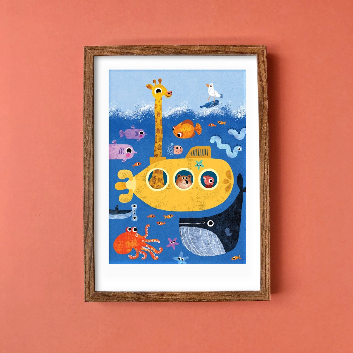 Framed children's illustration of a yellow submarine with sea creatures on a peach wall.