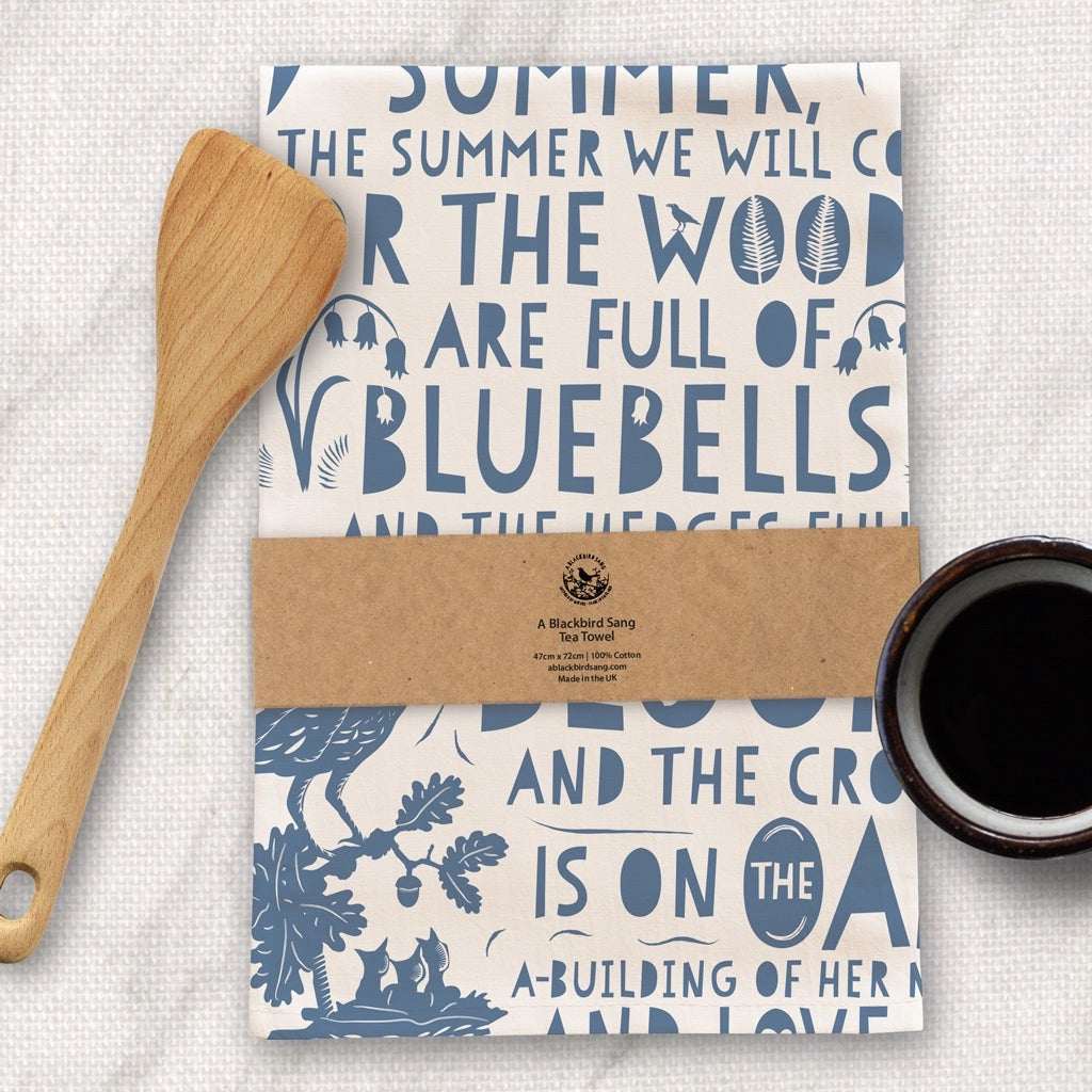 Packaged tea towel, wooden spoon, and cup of coffee on a textured surface