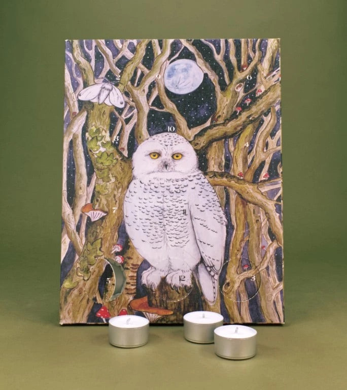 Advent Calendar featuring a snowy owl perched among bare tree branches under a full moon, displayed on an olive green surface with three silver tea light candles in front.