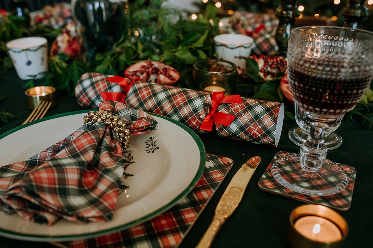 Tablescape with red and green tartan crackers and matching place setting.